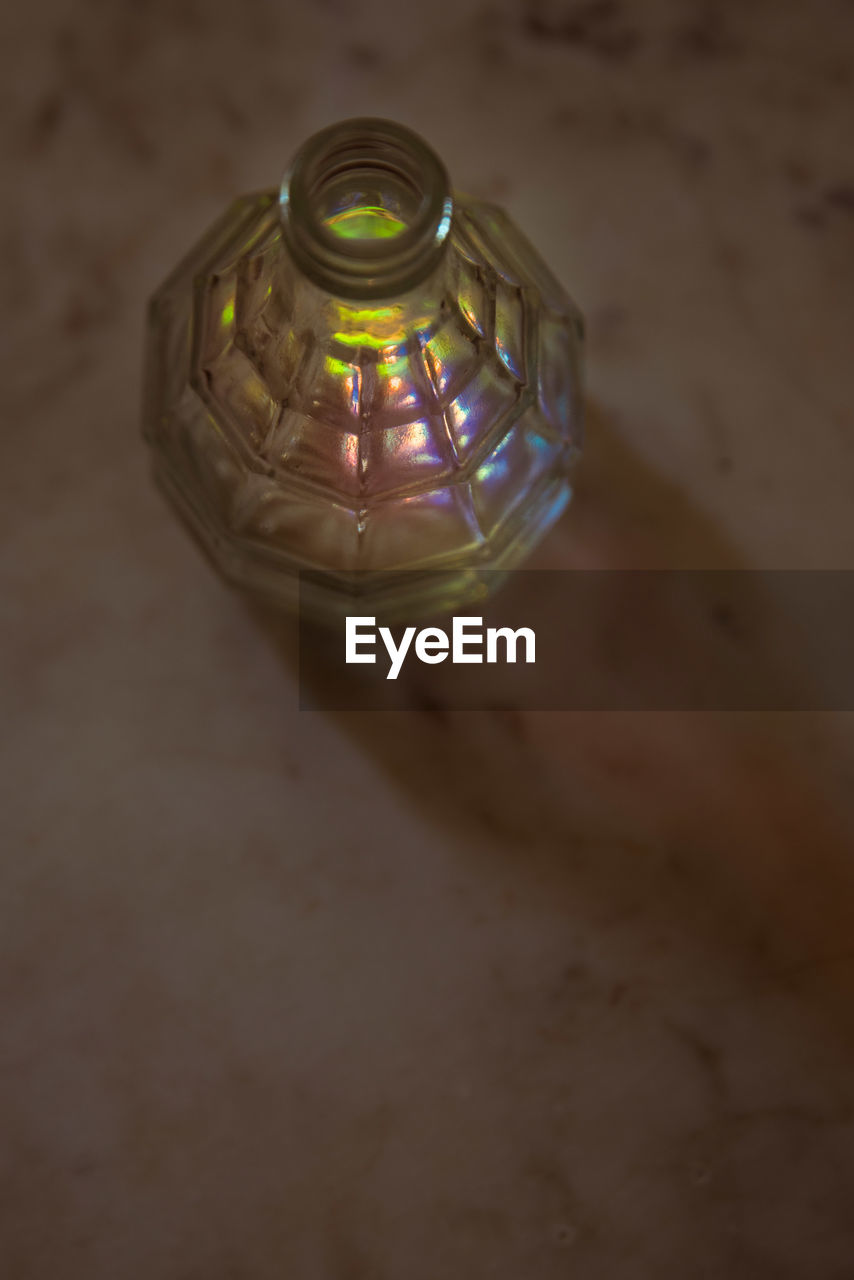 HIGH ANGLE VIEW OF ILLUMINATED LAMP ON TABLE IN GLASS