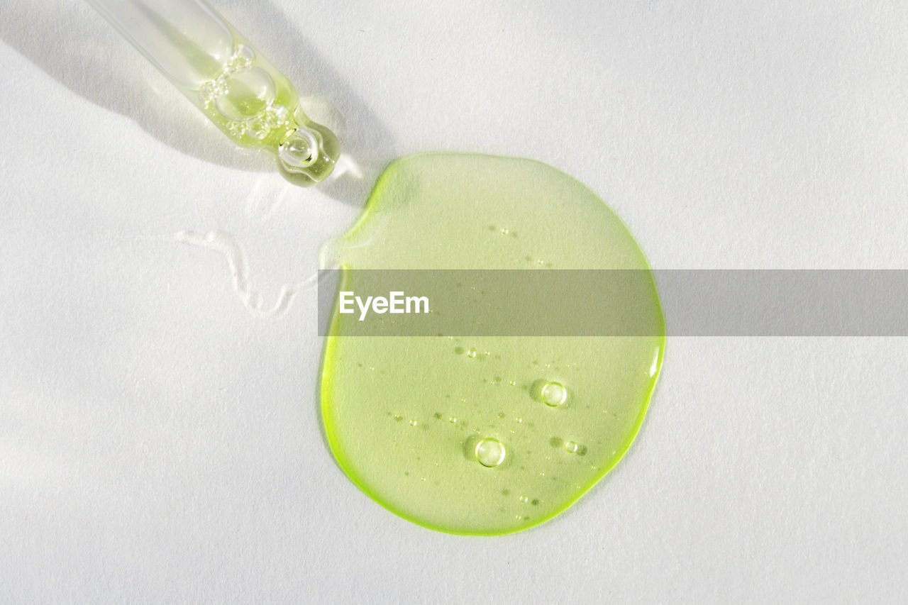 Pipette with green hyaluronic acid on white background. cosmetics, healthcare concept. dose of serum