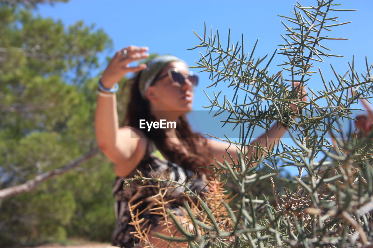 LOW ANGLE VIEW OF WOMAN ON PLANT