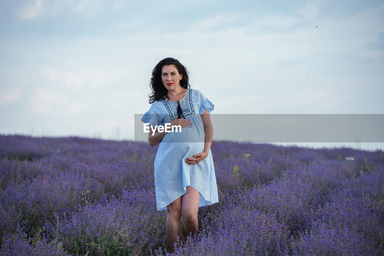 Full length of woman standing on field against sky