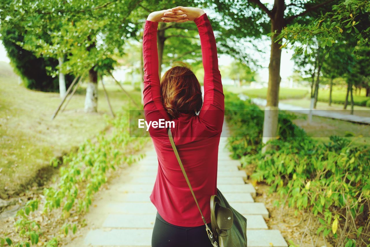 Rear view of woman with arms raised standing on walkway