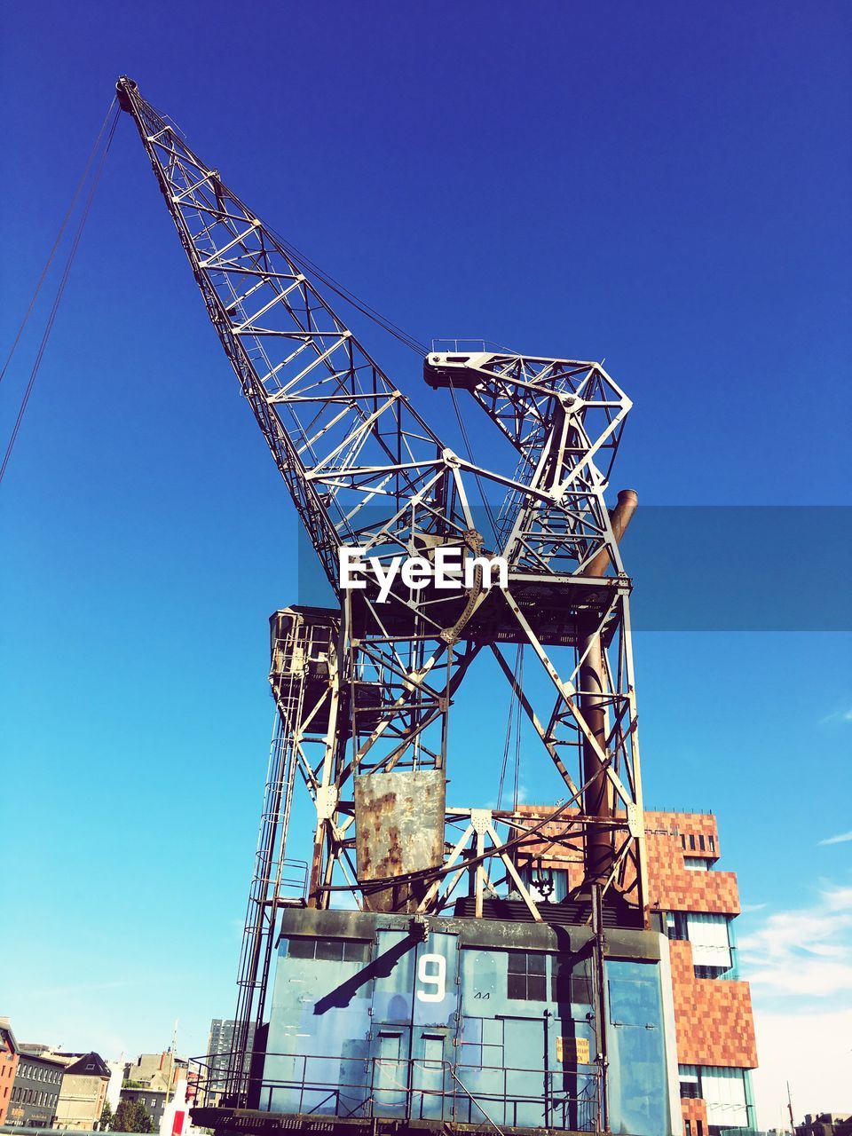 LOW ANGLE VIEW OF CRANES AGAINST BLUE SKY