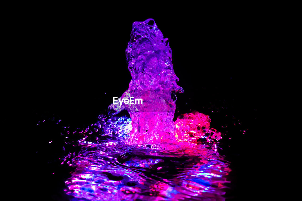 Close-up of pink water being splashed against black background