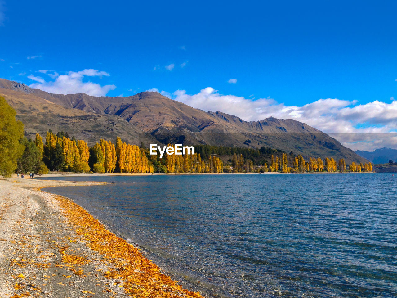 Scenic view of lake by mountains against blue sky