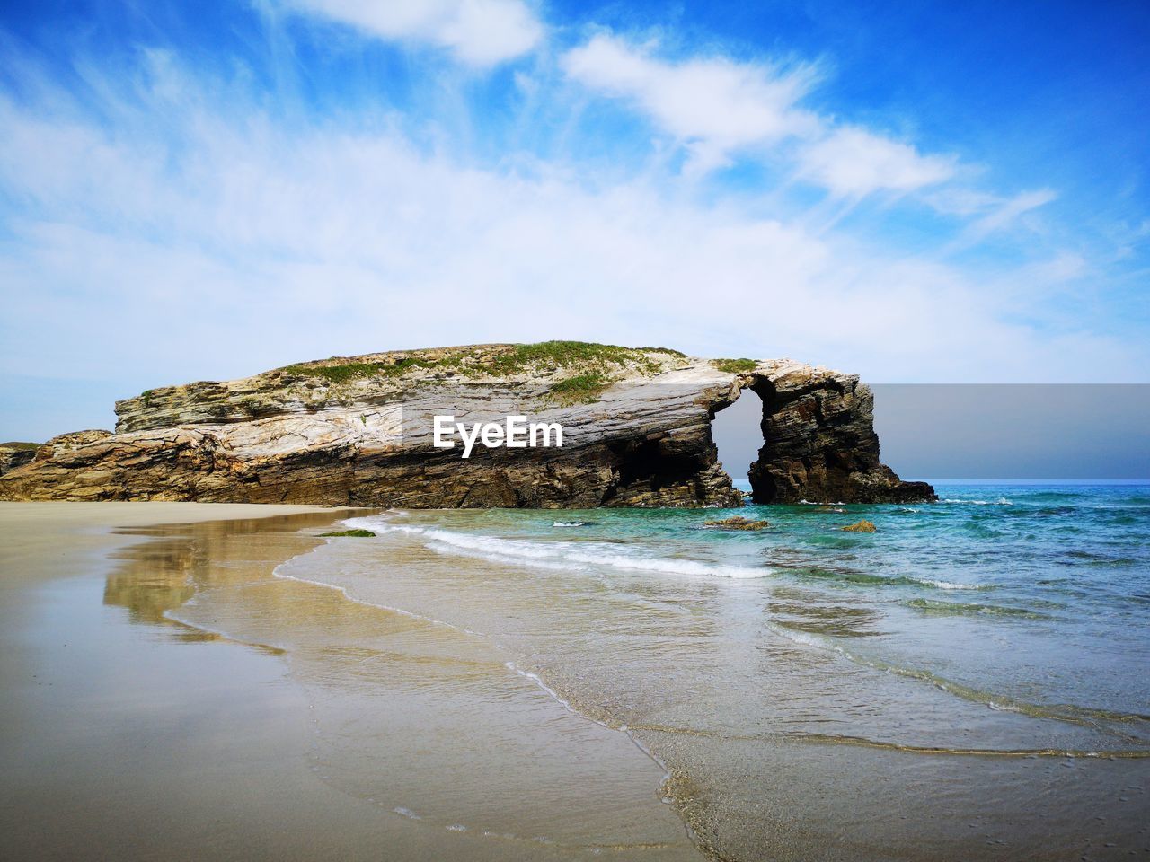 Rock formation on beach against sky