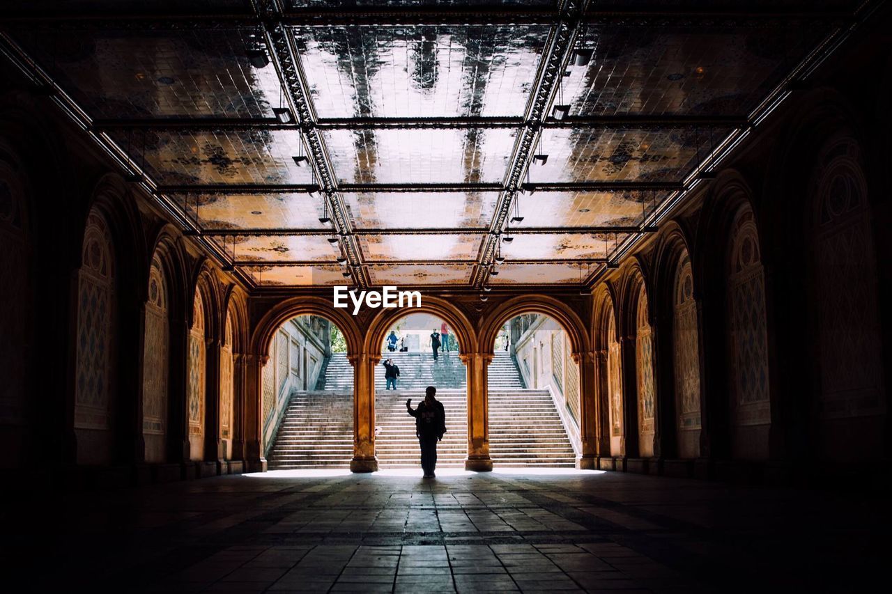 Silhouette man walking under arched ceiling