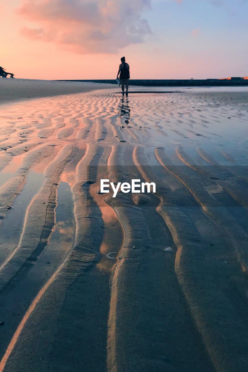 Silhouette man standing on beach against sky during sunset