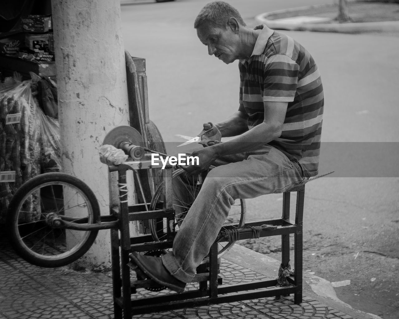 Side view of senior man sharpening scissors on footpath