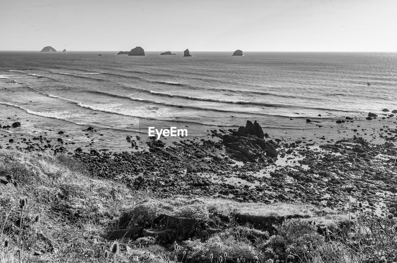 land, black and white, sea, sky, scenics - nature, beach, water, nature, environment, monochrome photography, landscape, monochrome, coast, tranquility, beauty in nature, tranquil scene, horizon, shore, horizon over water, day, wave, no people, non-urban scene, sand, travel destinations, outdoors, rock, travel, ocean, tourism, clear sky, idyllic, sunlight