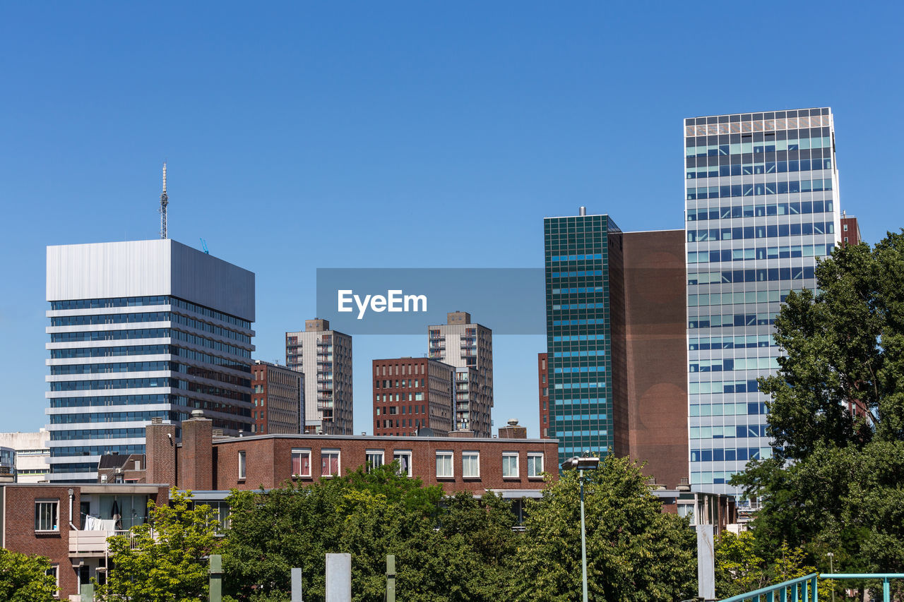 Buildings in city against clear blue sky