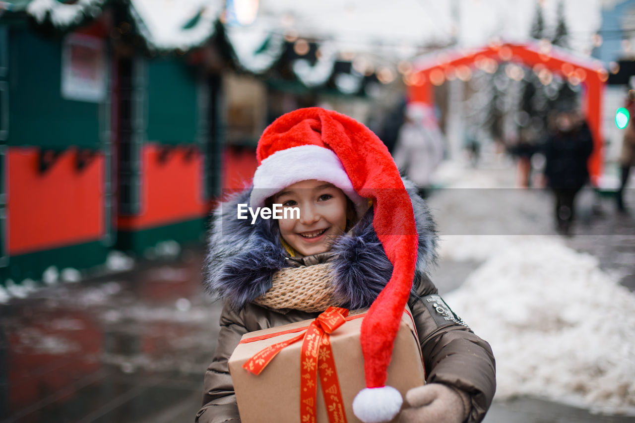 Portrait of girl holding gift box while standing outdoors