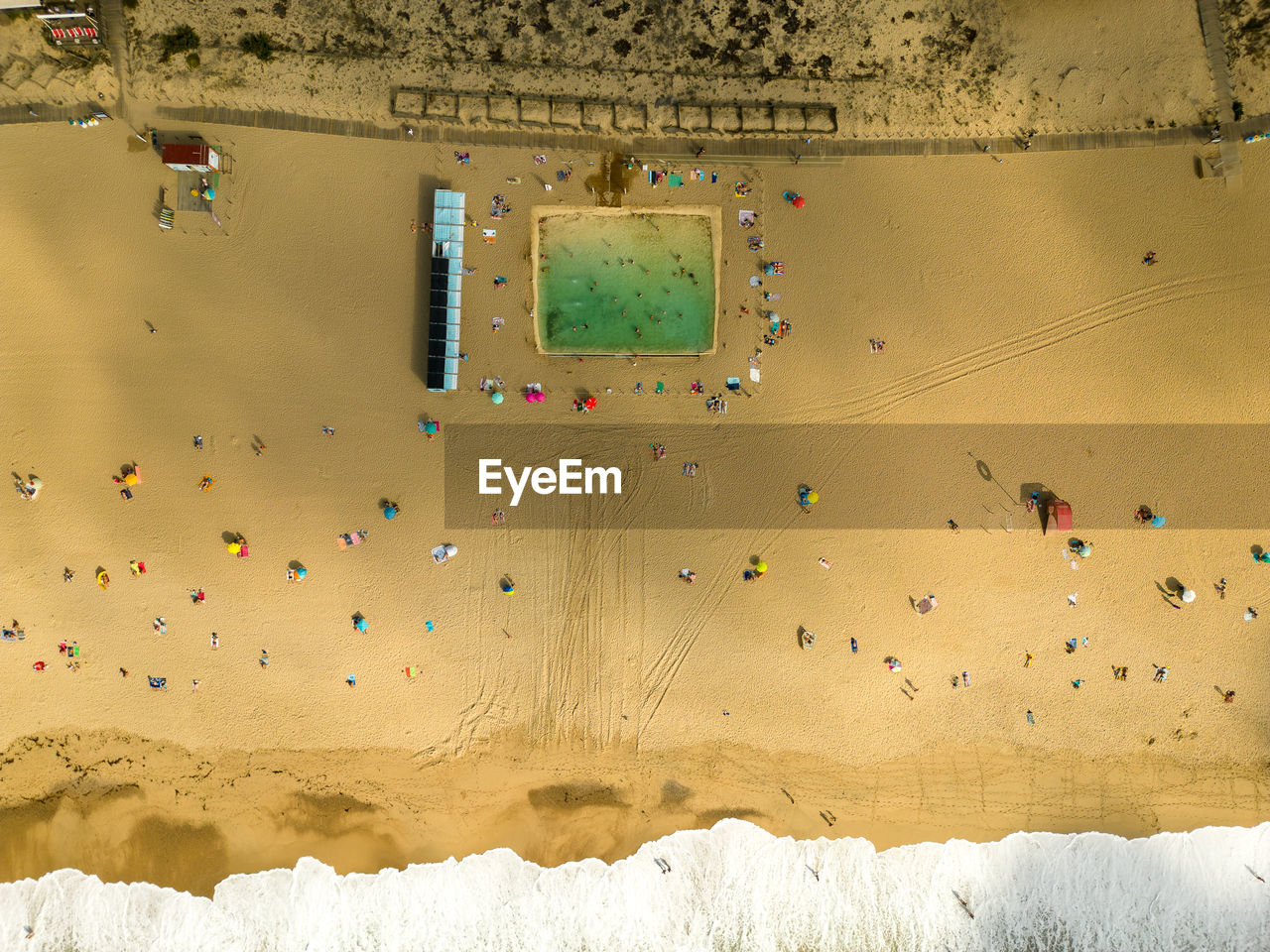 People on a beach with an artificial pool 