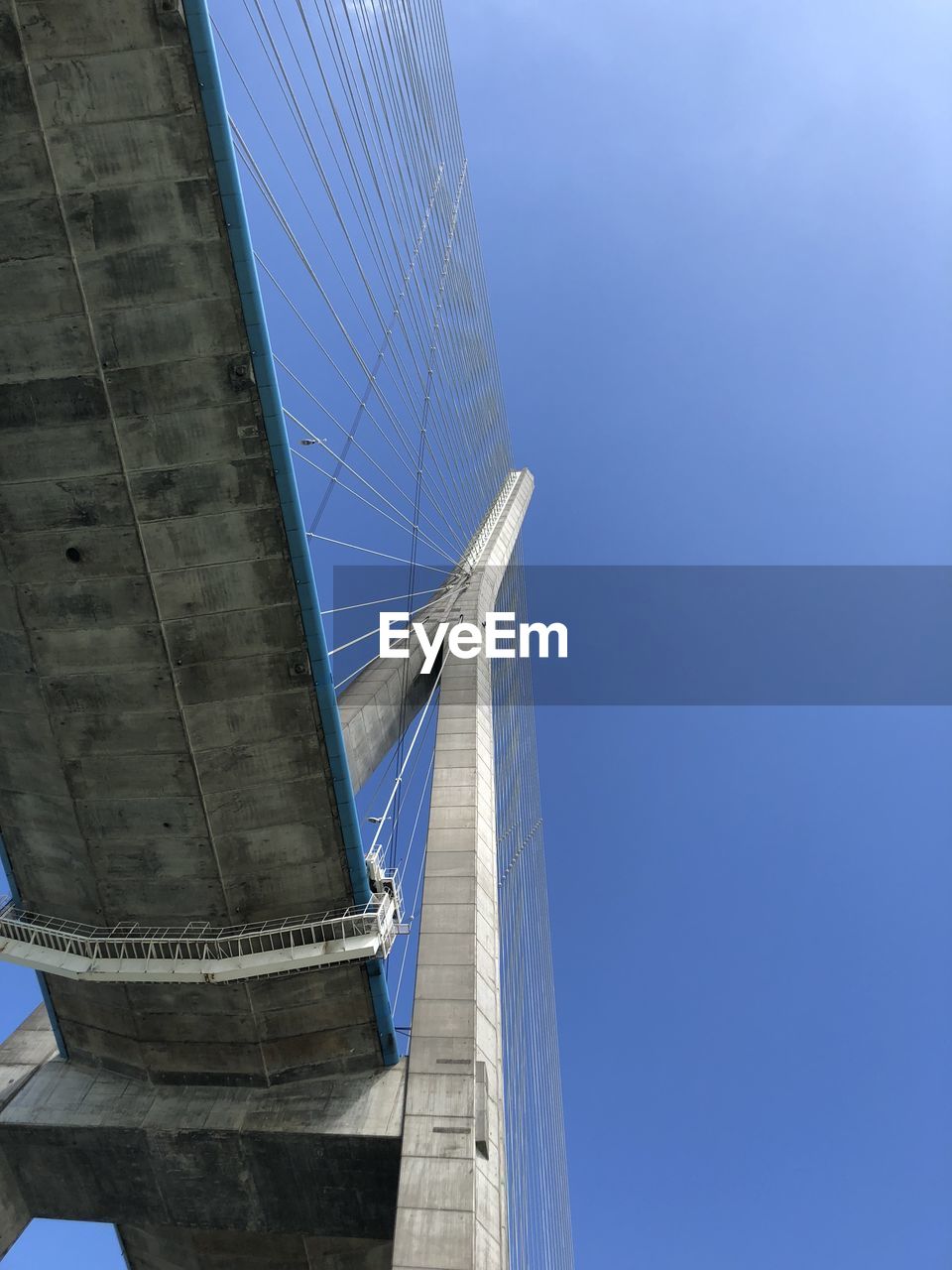 LOW ANGLE VIEW OF BRIDGE AGAINST BLUE SKY IN CITY