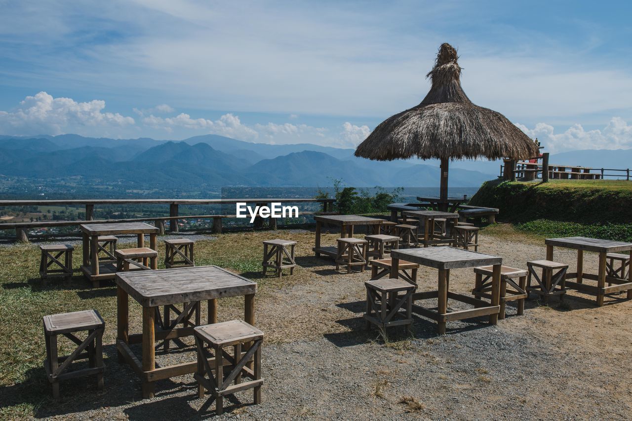EMPTY CHAIRS AND TABLE AGAINST MOUNTAINS