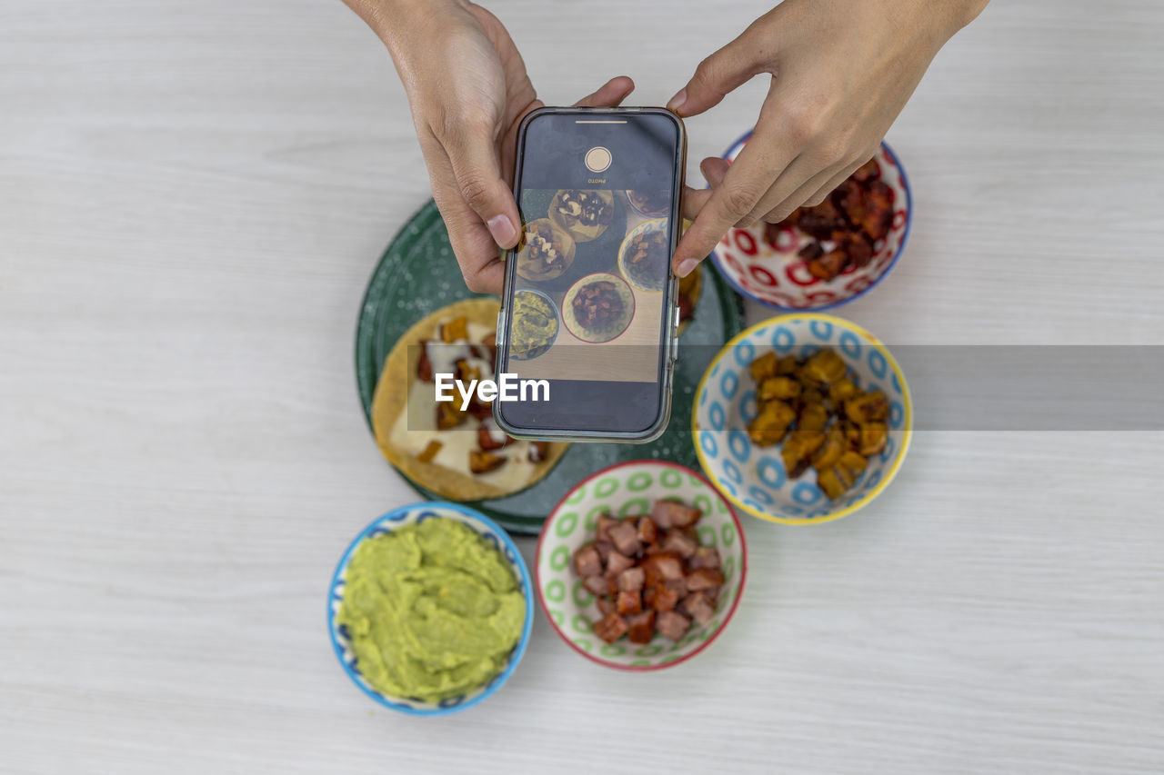 Hands with cell phone photographing a freshly prepared mexican meal