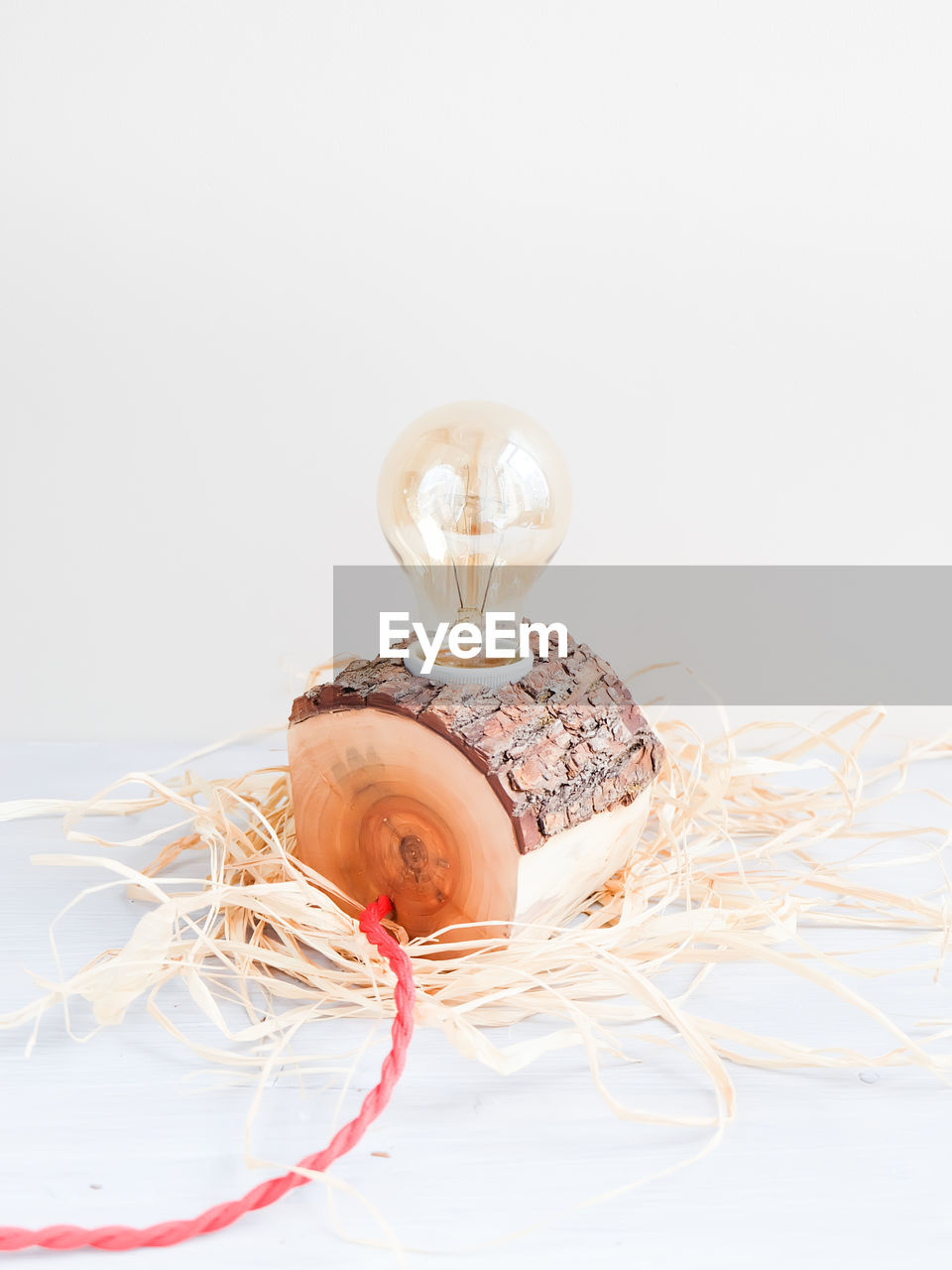 Close-up of light bulb on wood against white background