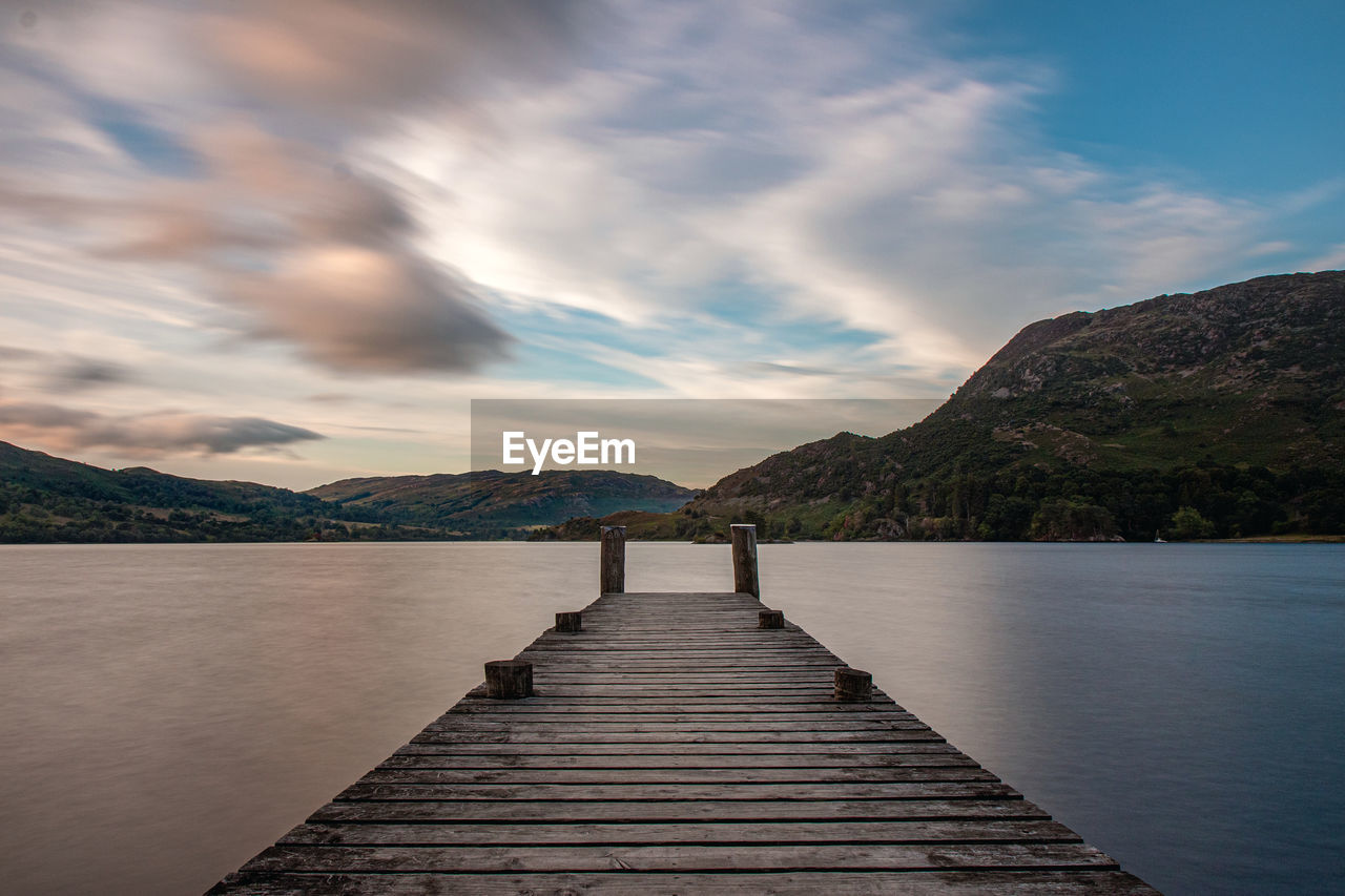 PIER OVER LAKE AGAINST MOUNTAINS