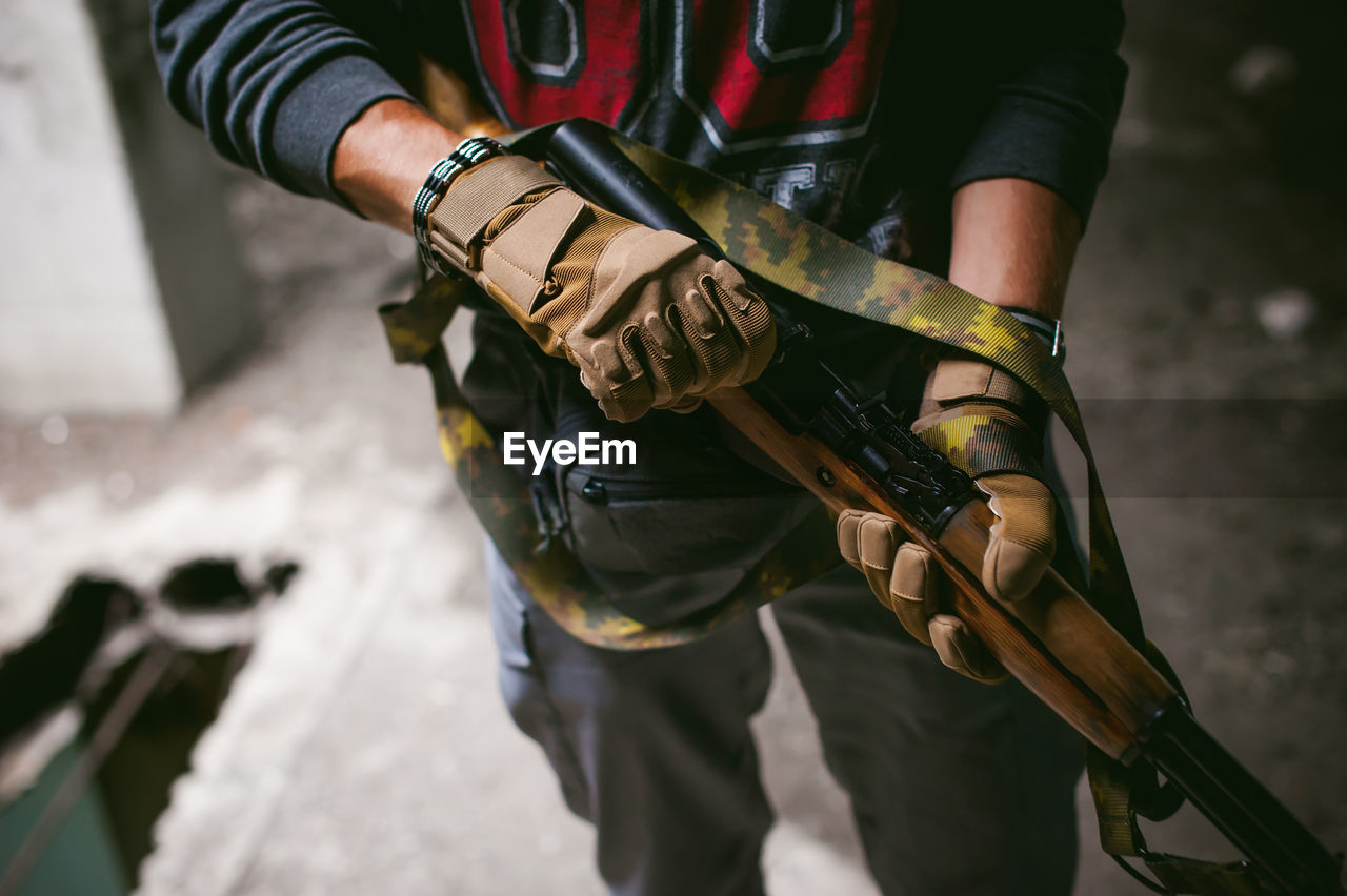 Midsection of man holding rifle