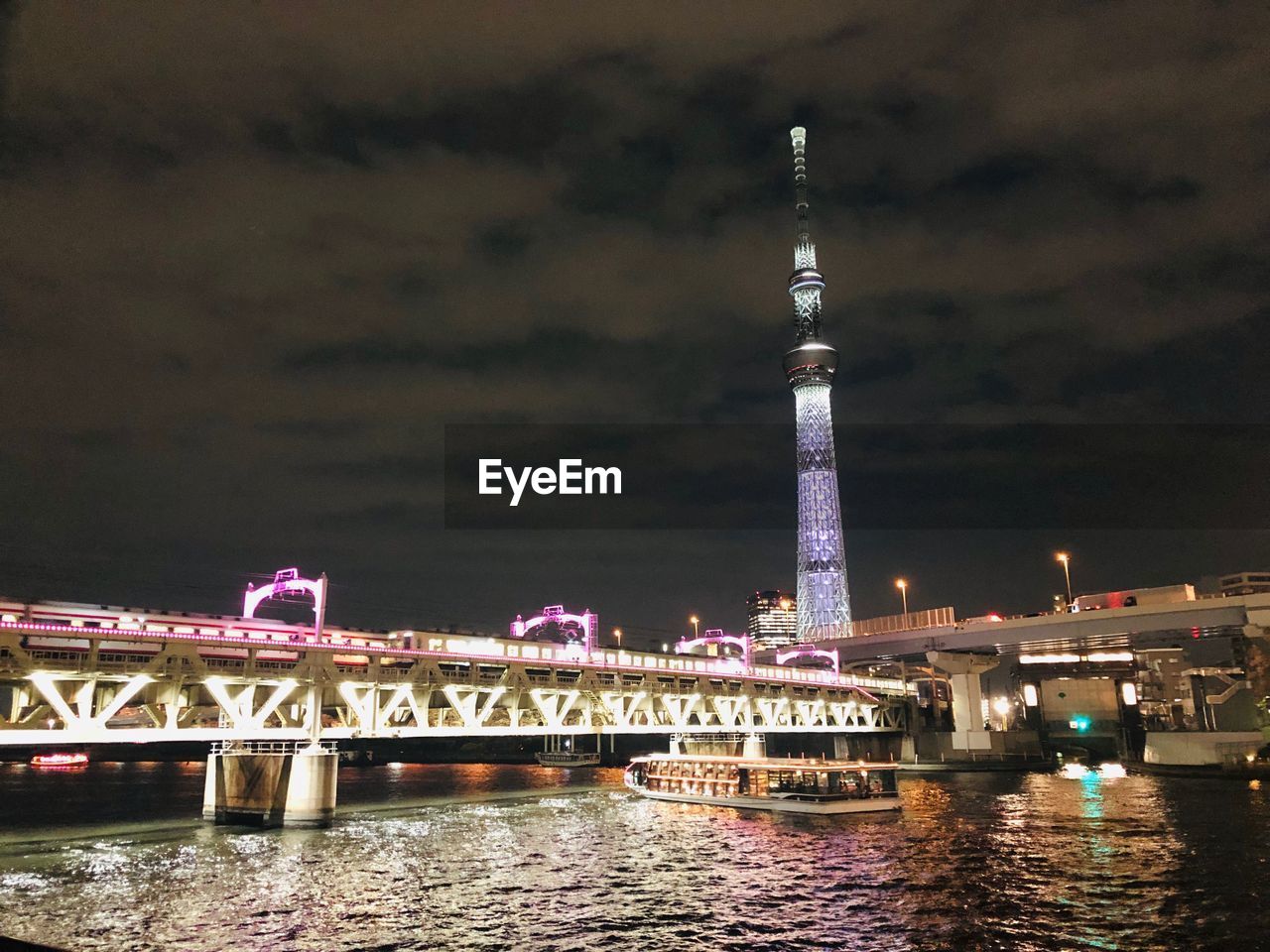 Illuminated bridge over river in city at night