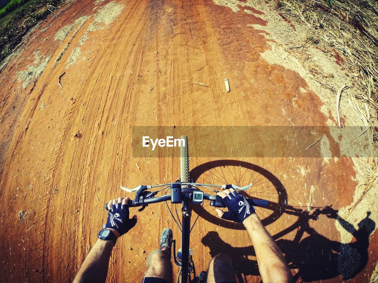 Low section of man riding bicycle on dirt road