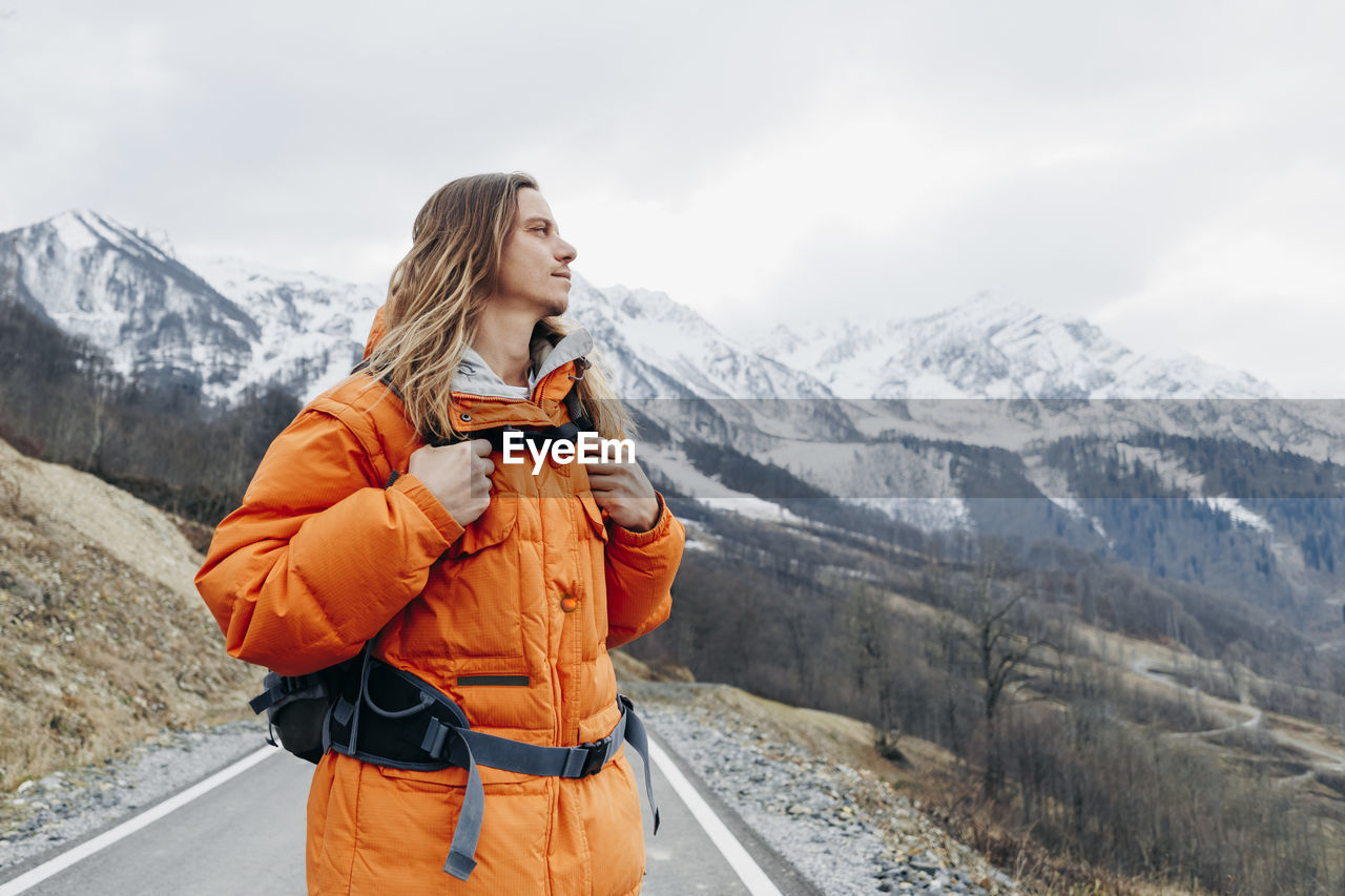 Contemplative man in orange jacket at winter vacation