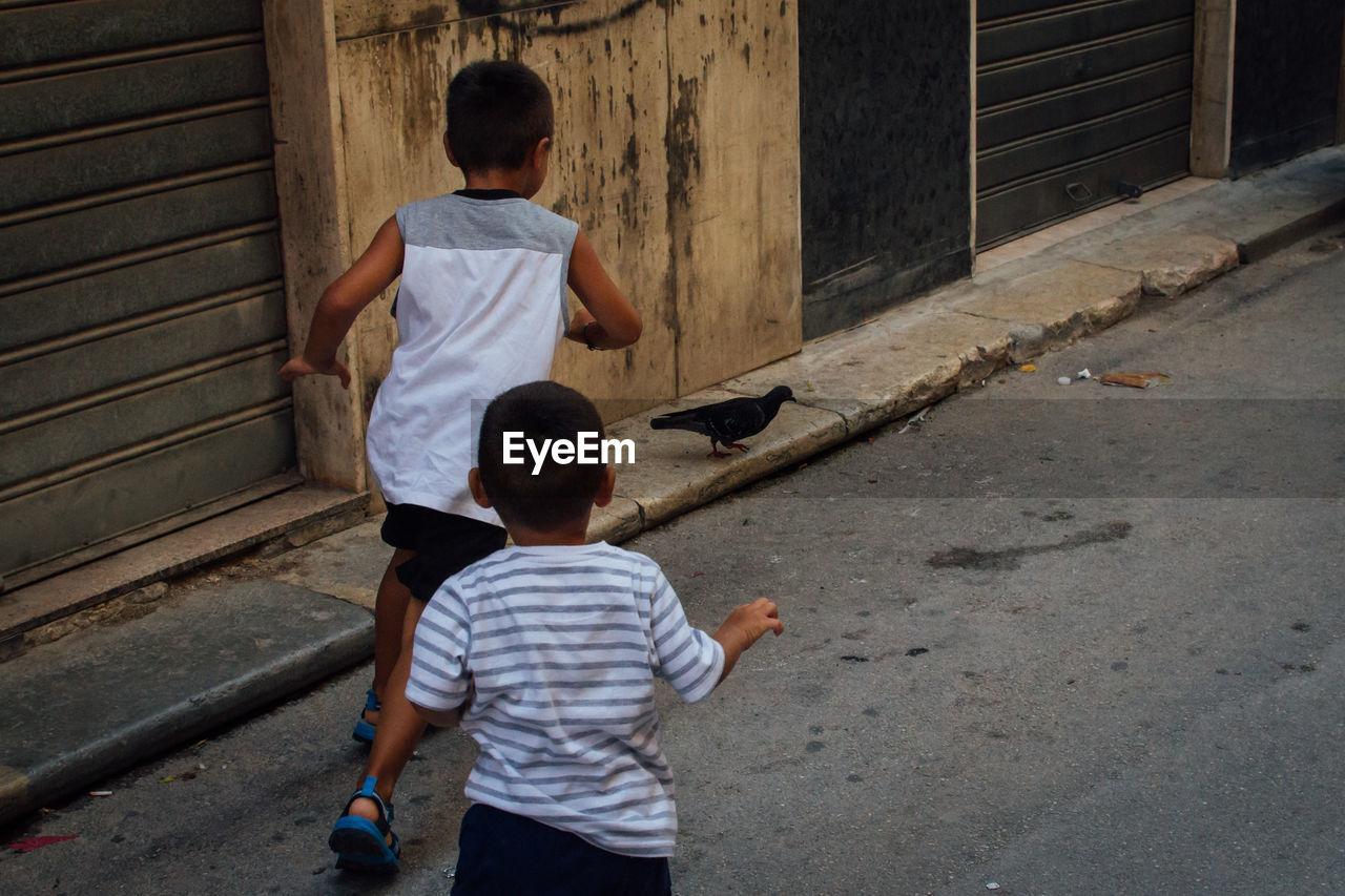 Rear view of boys playing on street