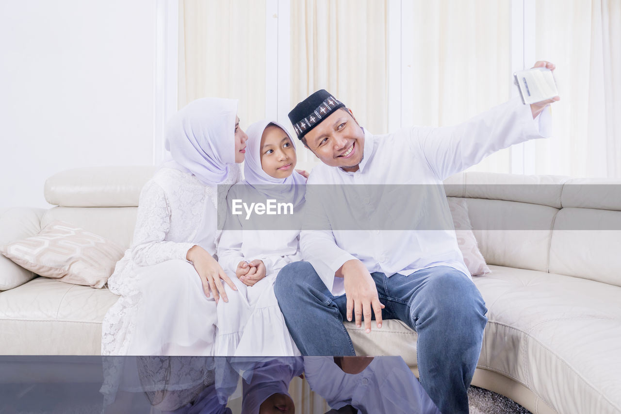 Cheerful family doing selfie while sitting at home