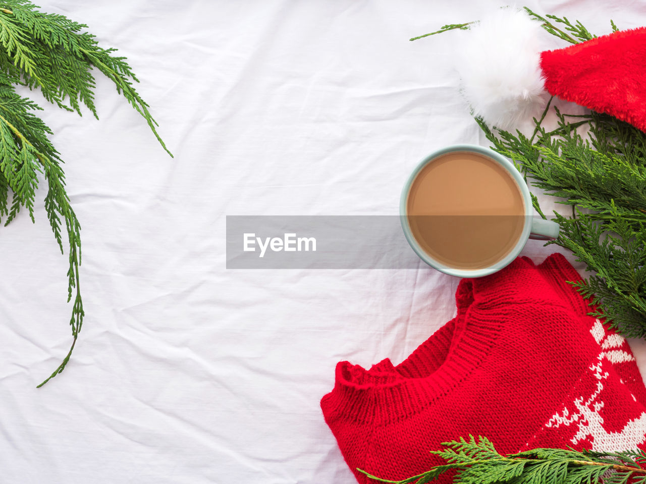 Winter cozy coffee mug, red sweater on background with branches