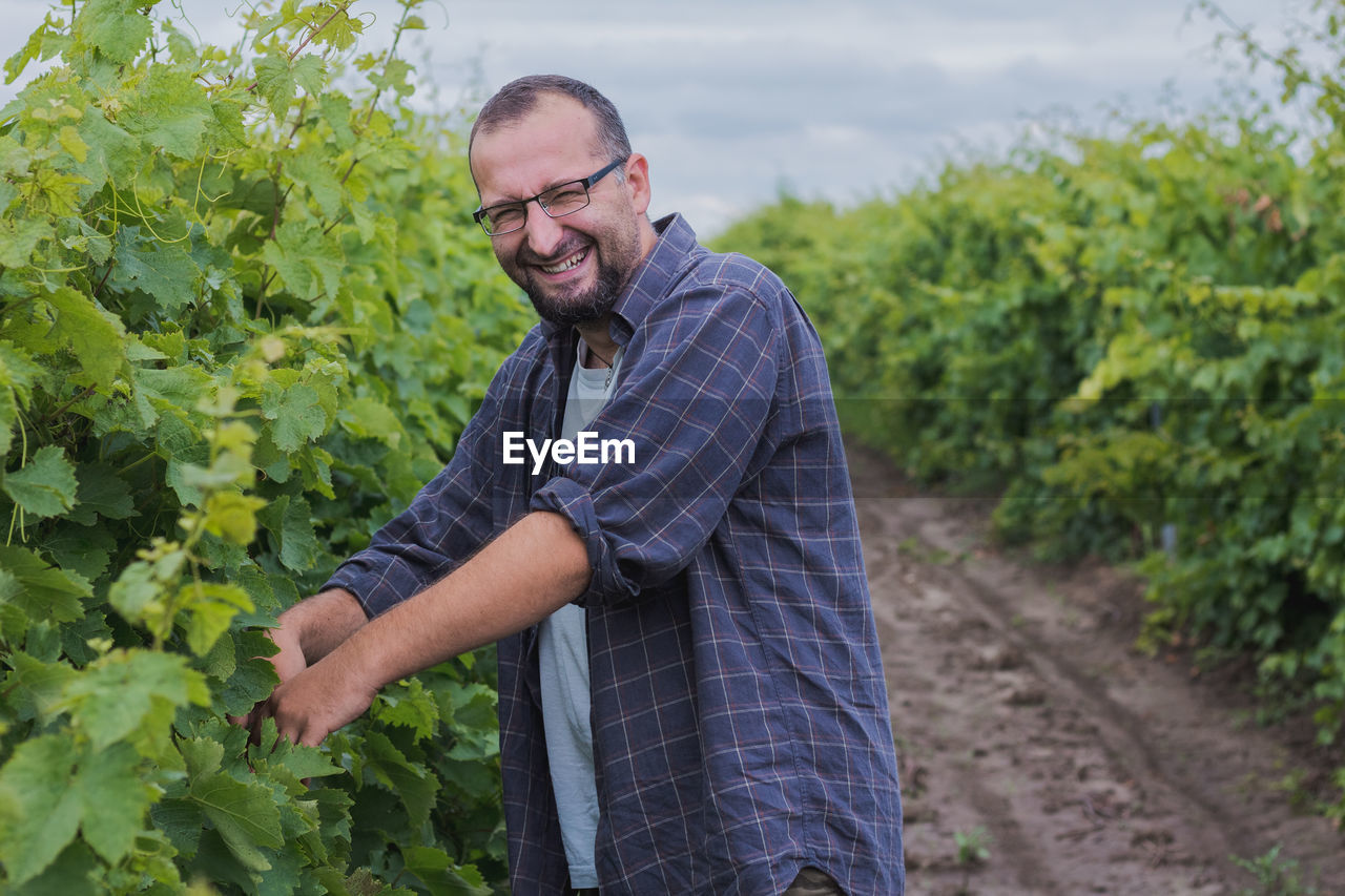 Portrait of smiling man harvesting berries on field