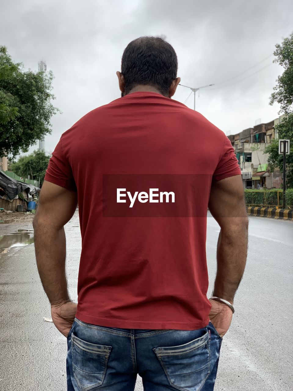 REAR VIEW OF MAN STANDING ON STREET IN CITY