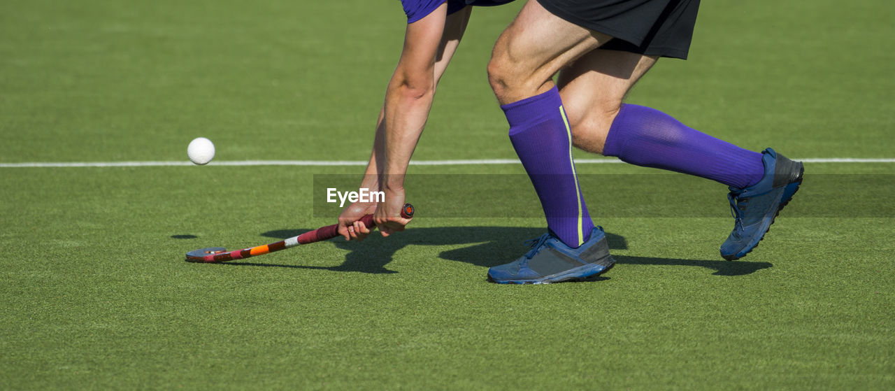 Low section of man playing hockey on turf