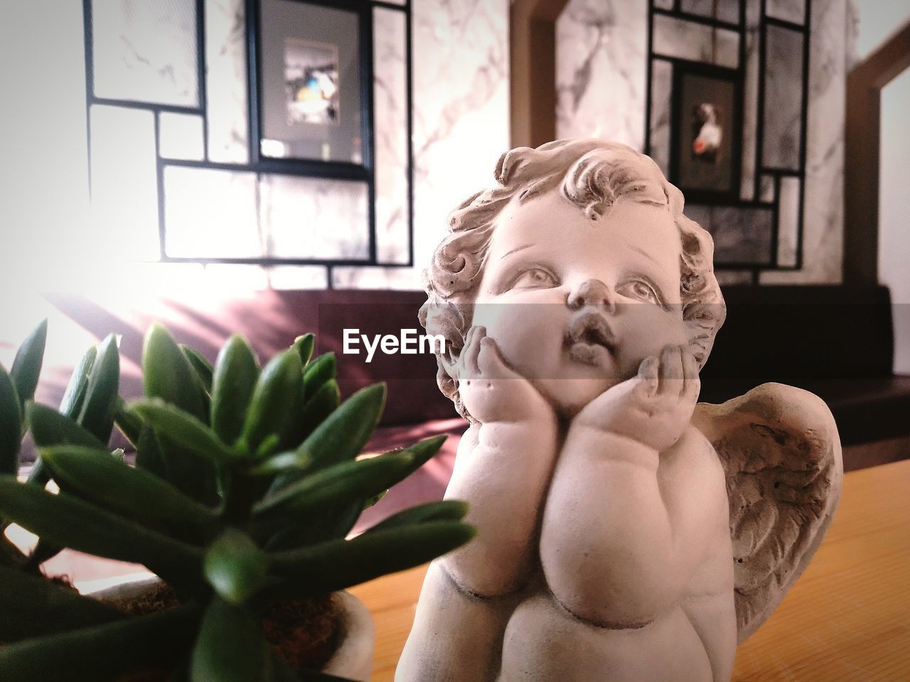 CLOSE-UP OF STATUE BY POTTED PLANT ON TABLE