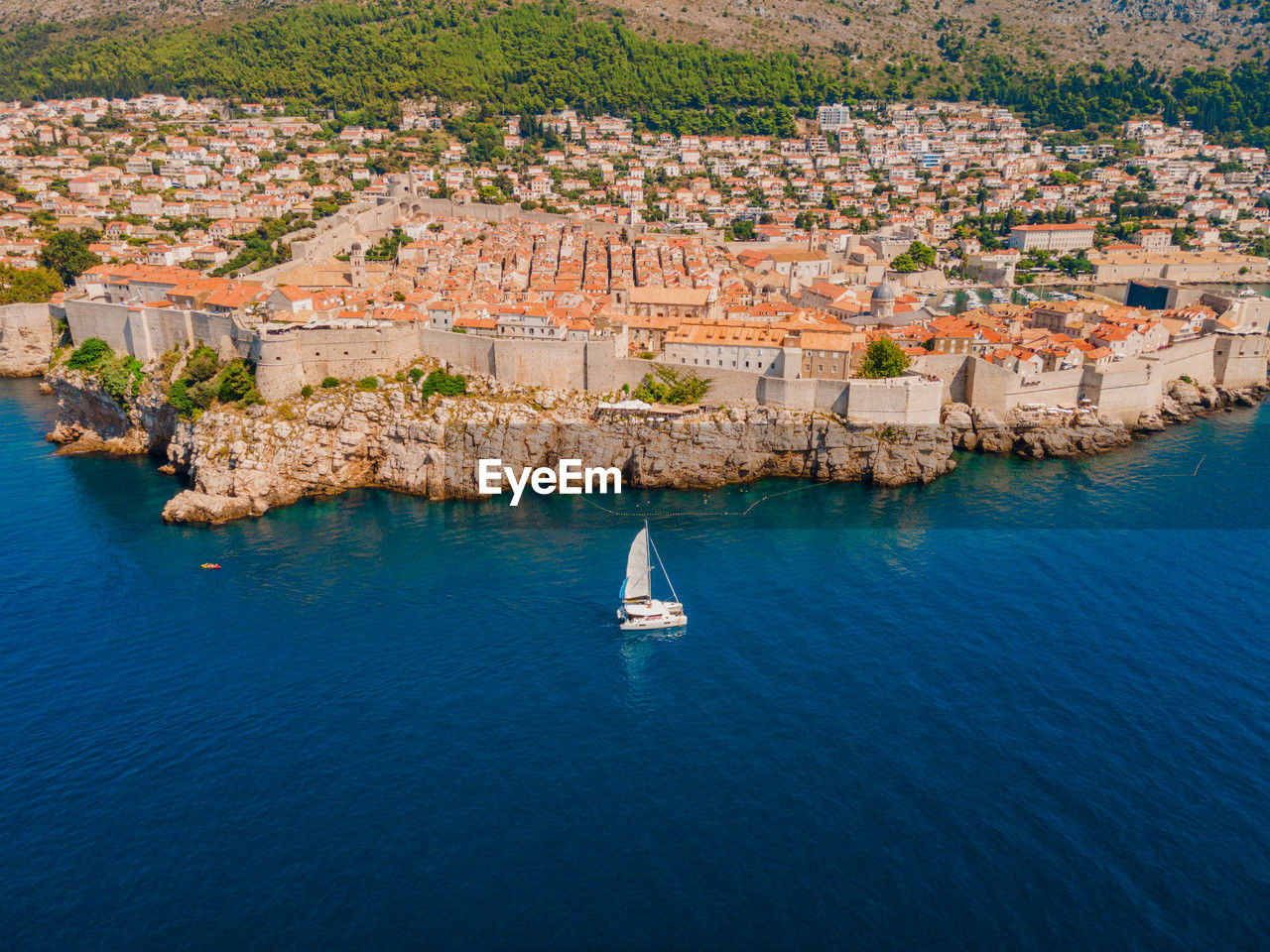 Aerial view of dubrovnik croatia old town in summer with sailing yacht catamaran passing.