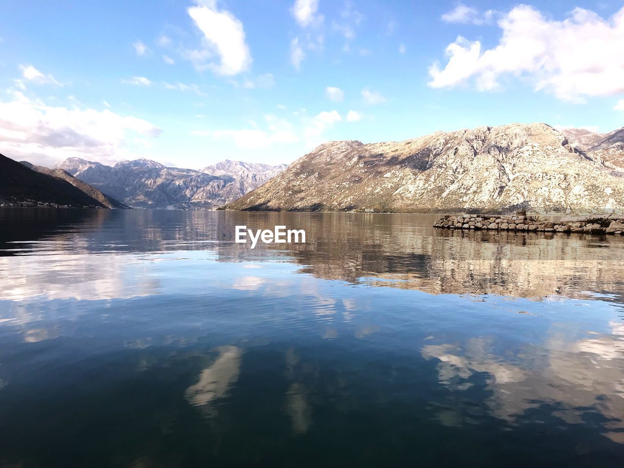 Scenic view of lake by mountain against sky