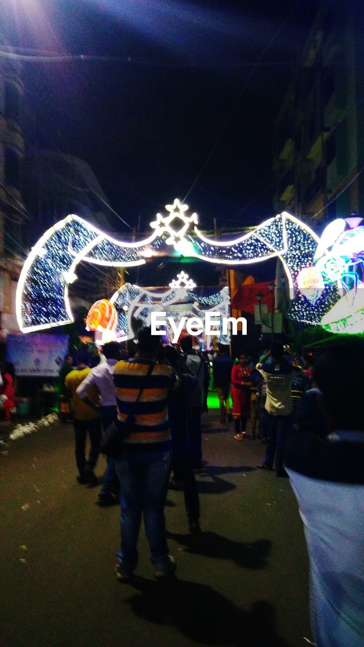 PEOPLE AT ILLUMINATED CAROUSEL IN CITY