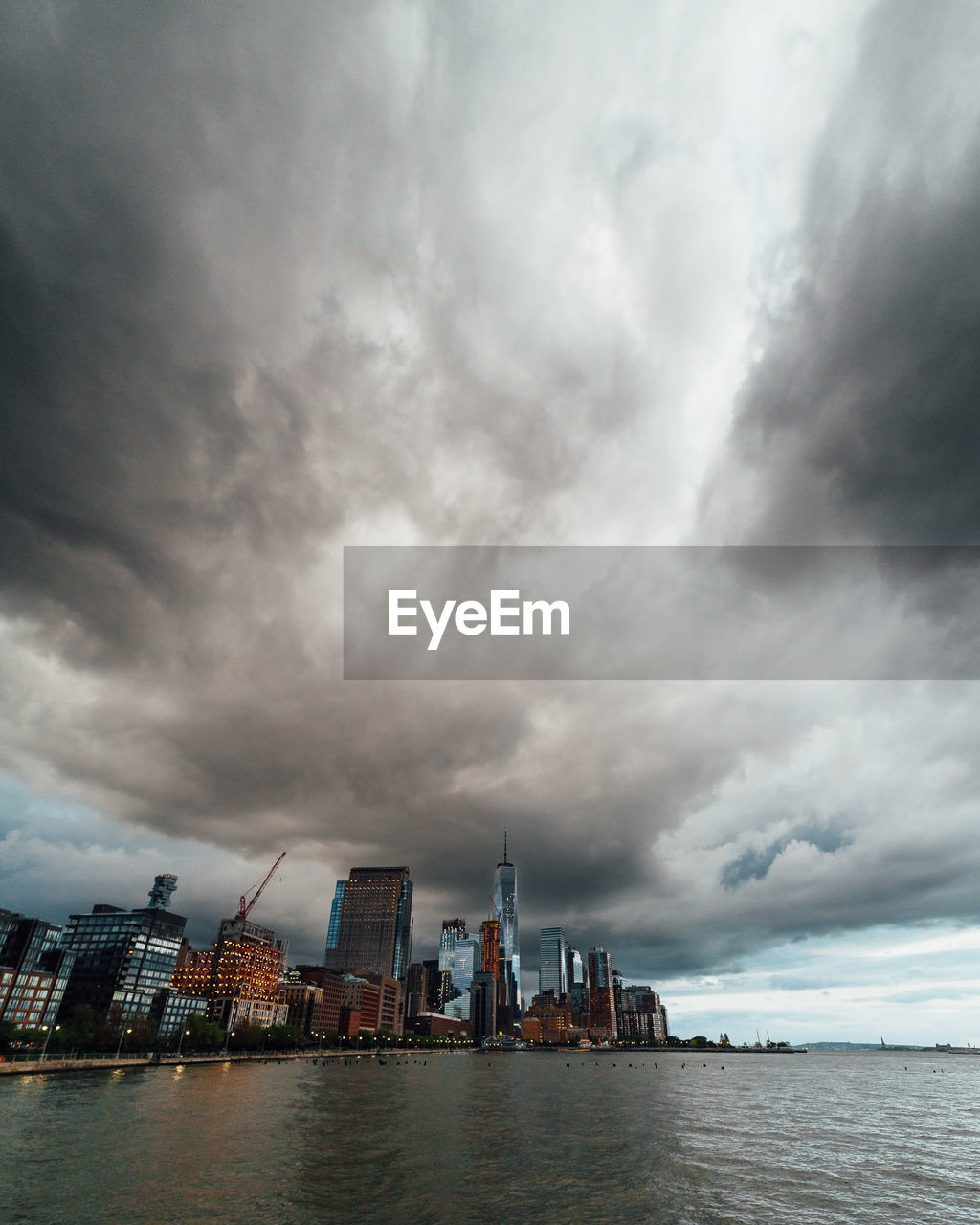 City at waterfront against cloudy sky