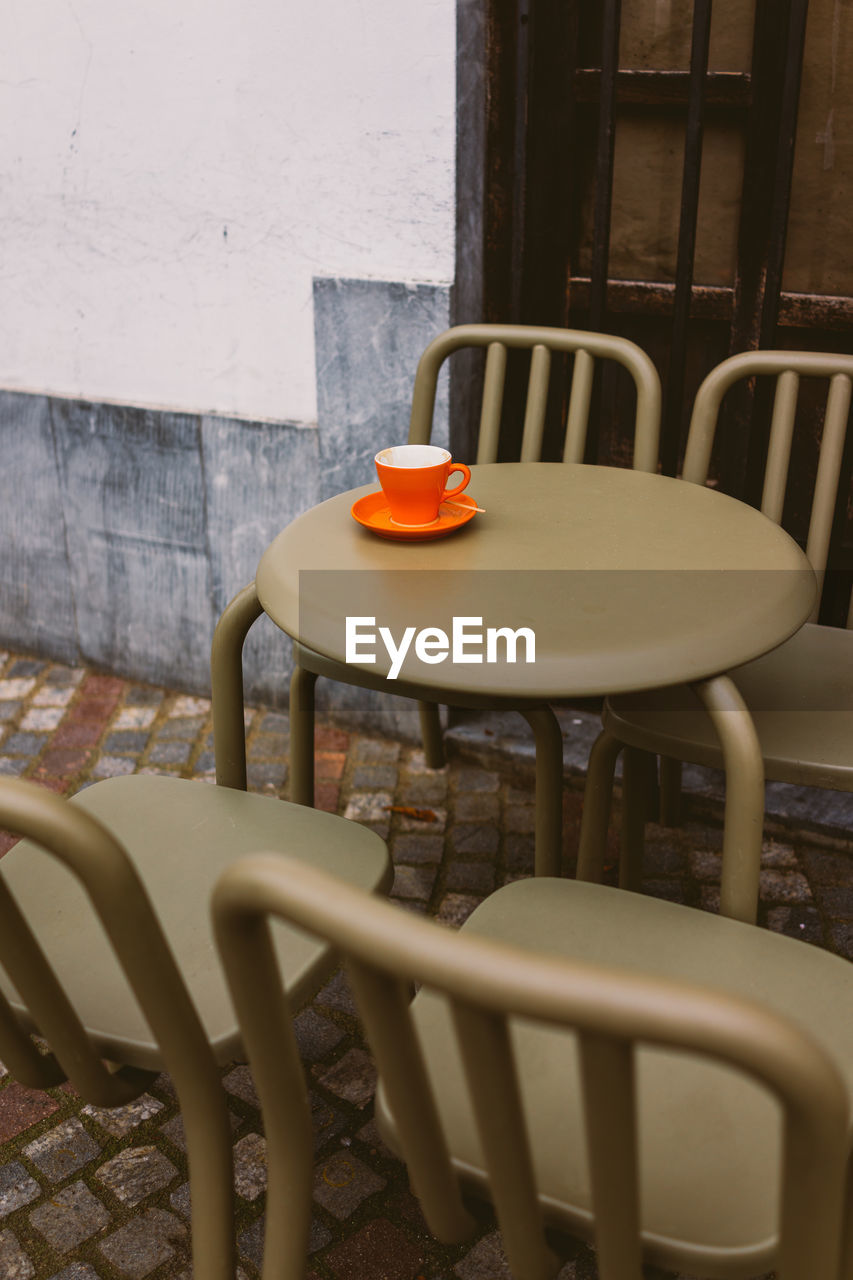 Empty chairs and coffee cup on table at sidewalk cafe