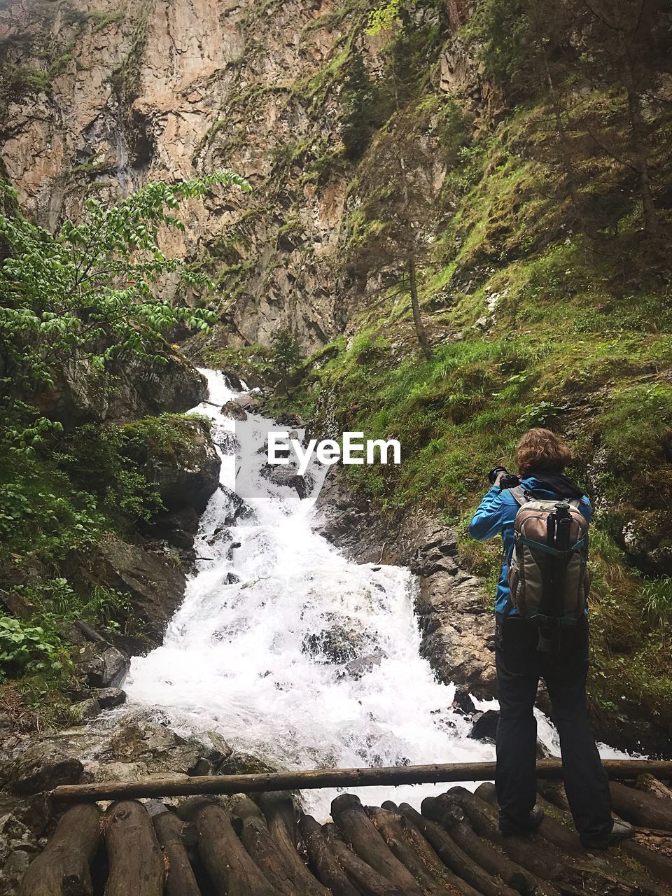 MAN STANDING AMIDST WATERFALL