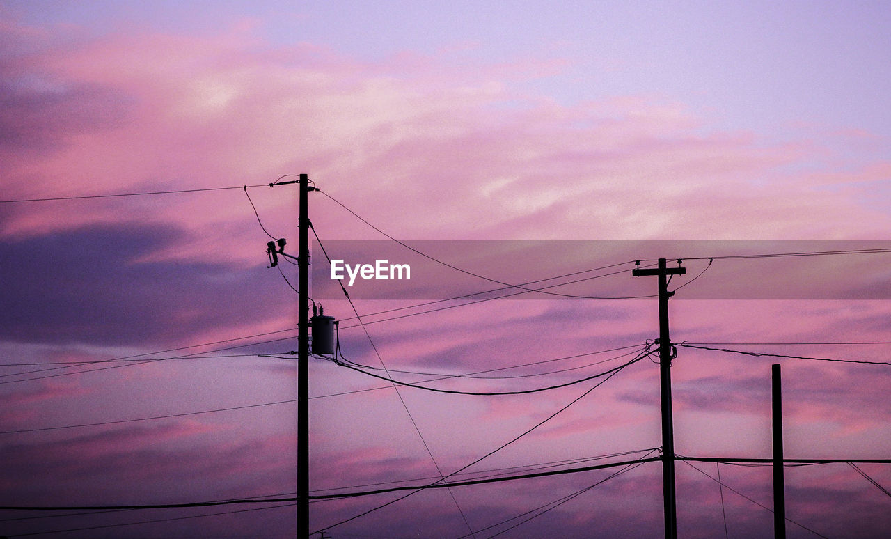 Low angle view of electricity pylon against purple sky