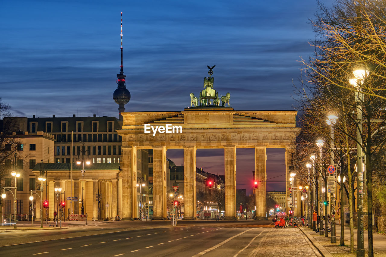The famous brandenburg gate in berlin with the television tower at dawn