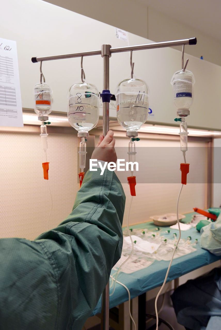 Cropped hand on doctor holding iv drip stand in wardroom at hospital