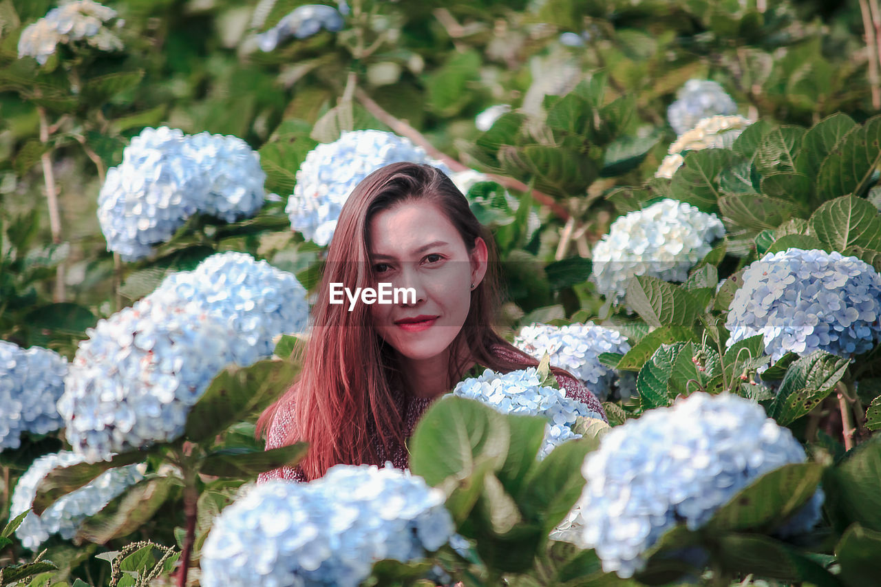 Portrait of smiling woman by flowering plants