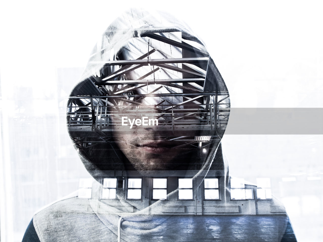 Double exposure of architecture and man wearing hooded jacket