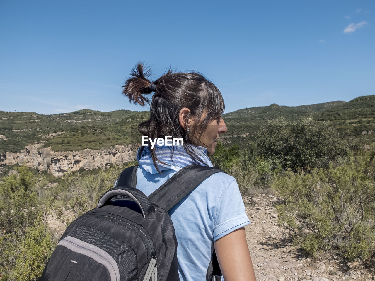 side view of young woman standing on field against sky