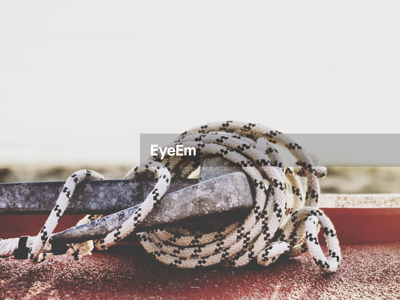 Close-up of rope tied up on metal against clear sky