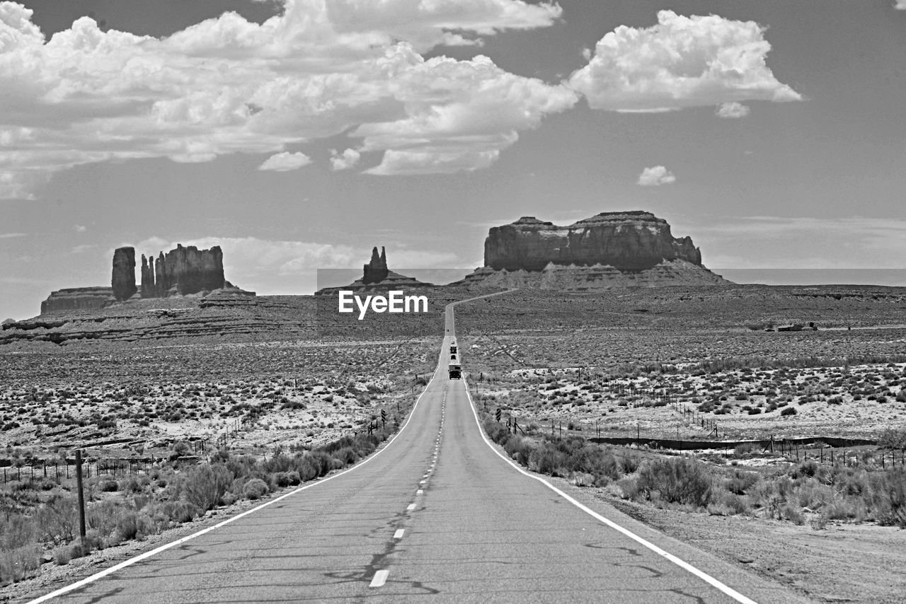 Road passing through landscape against cloudy sky