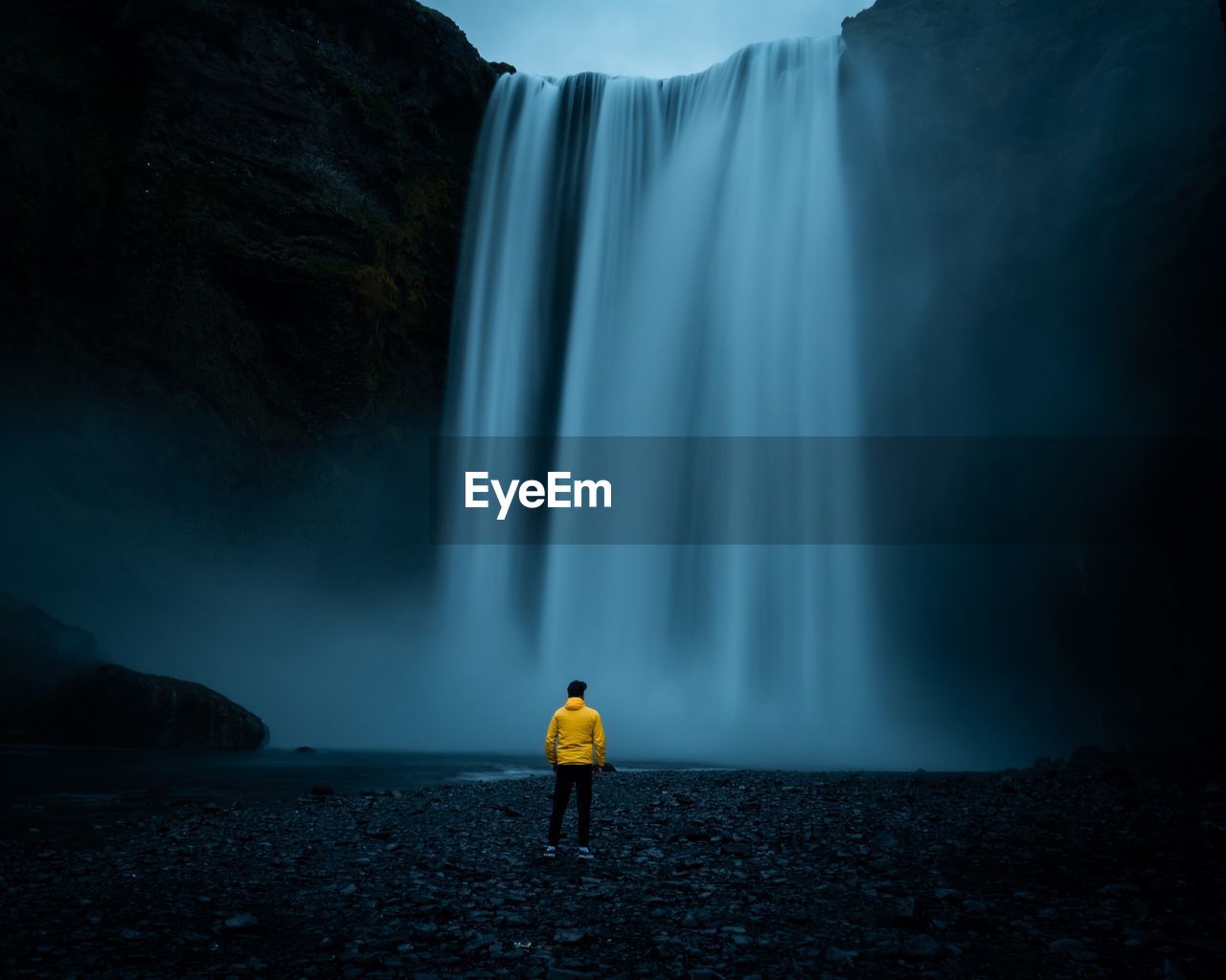 Rear view of man looking at waterfall