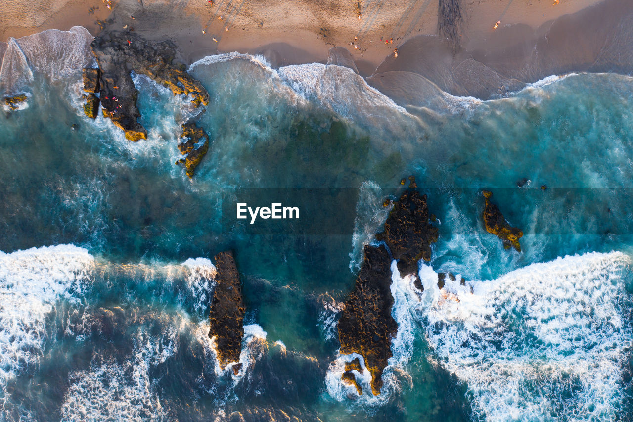 Aerial view of waves splashing on rocks at beach