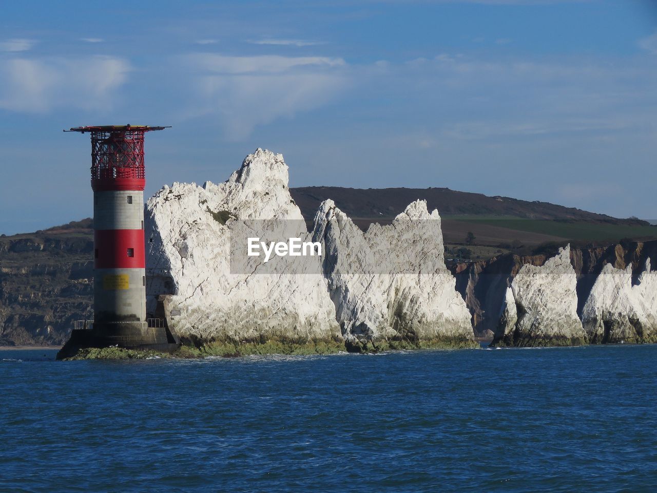 Lighthouse by sea against sky