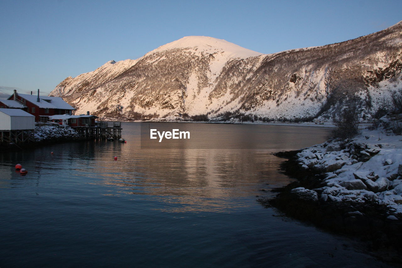 Scenic view of lake by snowcapped mountains against clear sky